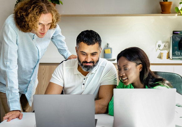 Three colleagues having discussion around computer.